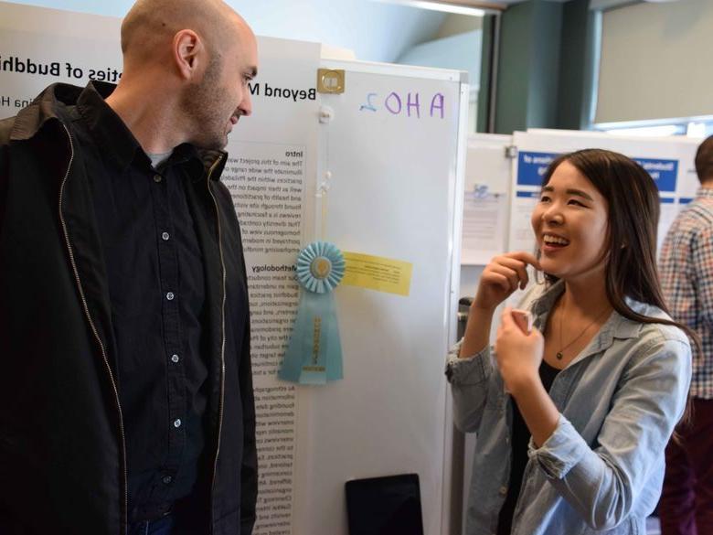 two students talking in front of poster board